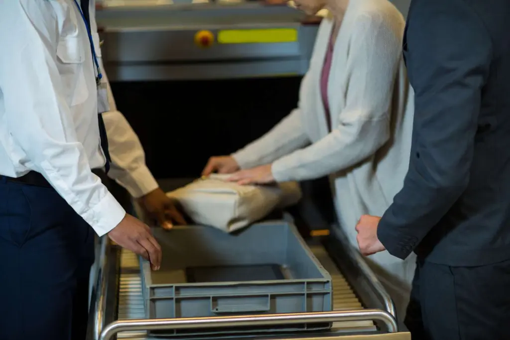 oficial de seguranca do aeroporto verificando a mala do passageiro 1 2