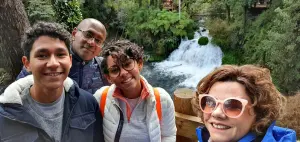 familia de quatro pessoas com cahoeira ao fundo em expedicao sul do chile
