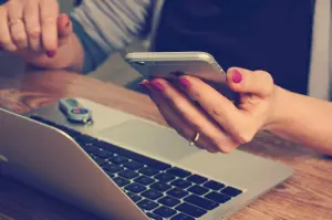 mãos femininas usando celular e notebook para fazer cotação no Chile